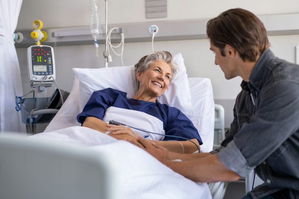 Son visiting his smiling mother at hospital